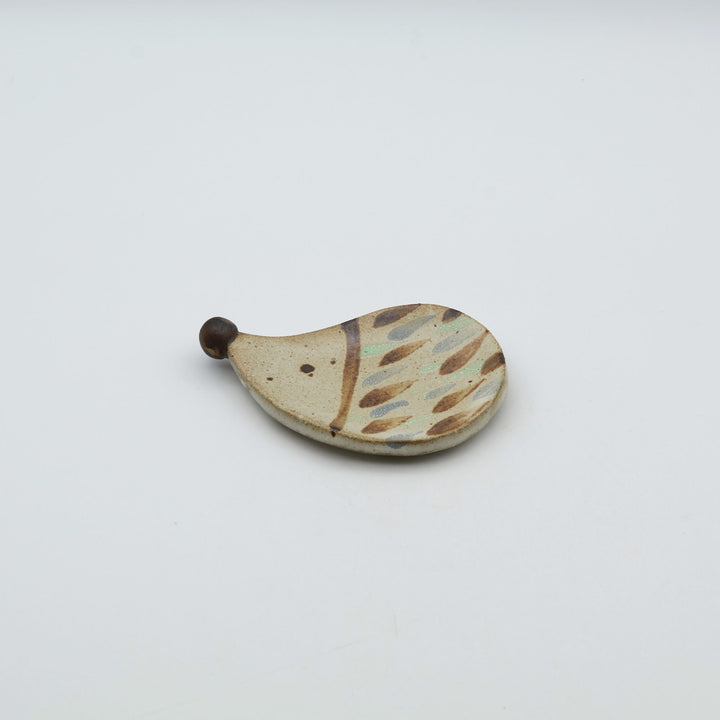 ハリネズミを模った小ぶりなやちむんの豆皿。茶色のドットで針が表現されており、つぶらな瞳と突き出した鼻が特徴的な、カトラリーレストにもなる｢土の種」の作品。