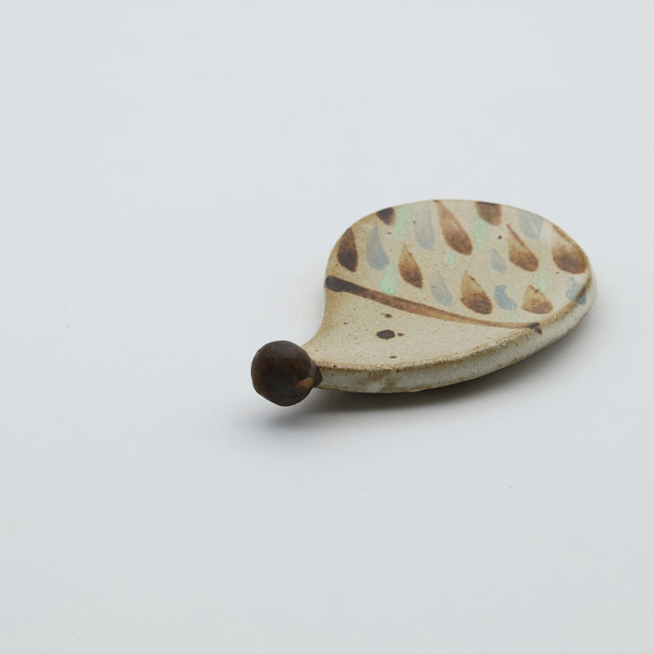 ハリネズミを模った小ぶりなやちむんの豆皿。茶色のドットで針が表現されており、つぶらな瞳と突き出した鼻が特徴的な、カトラリーレストにもなる｢土の種」の作品。