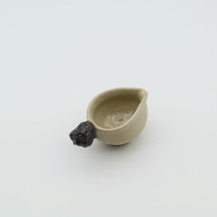 ゴツゴツとした岩のような黒い持ち手がついた、陶器製ミルクピッチャー。手仕事ならではの質感と適度な遊び心が魅力的な、小ぶりの器。自然の力強さと温かさを感じさせる、土の種を代表するやちむんのオリジナル作品。