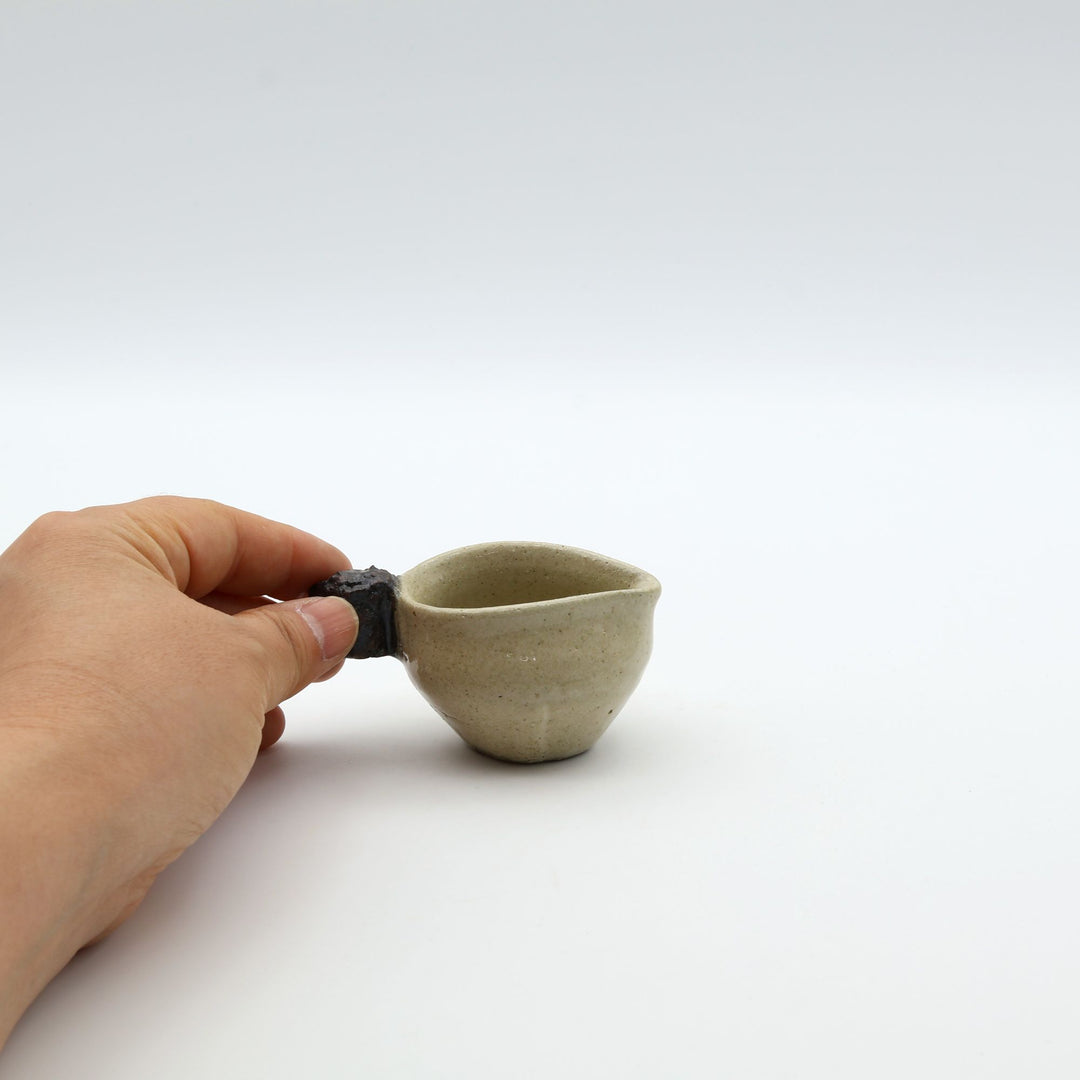 ゴツゴツとした岩のような黒い持ち手がついた、陶器製ミルクピッチャー。手仕事ならではの質感と適度な遊び心が魅力的な、小ぶりの器。自然の力強さと温かさを感じさせる、土の種を代表するやちむんの定番作品。
