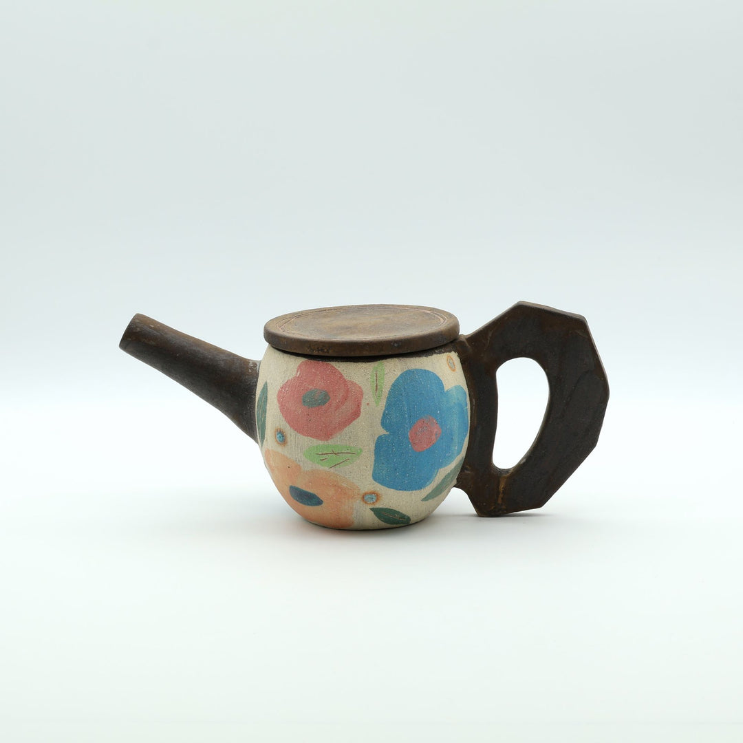 沖縄のやちむん「土の種」によるカラフルな花模様のポット。手描きのアートのような絵付けと、木の枝のような独特な持ち手が特徴的な一点物の器。