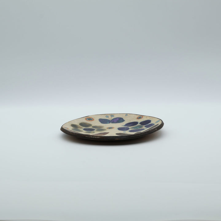 沖縄のやちむん工房「土の種」のサラダ皿。花に舞う蝶や鳥が大胆に絵付けされた手仕事の平皿。