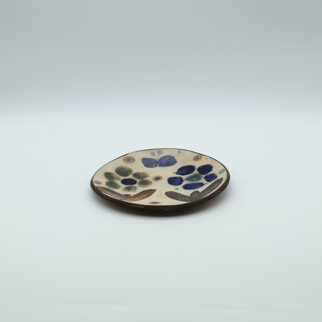 沖縄のやちむん工房「土の種」のサラダ皿。花に舞う蝶や鳥が大胆に絵付けされた手仕事の平皿。