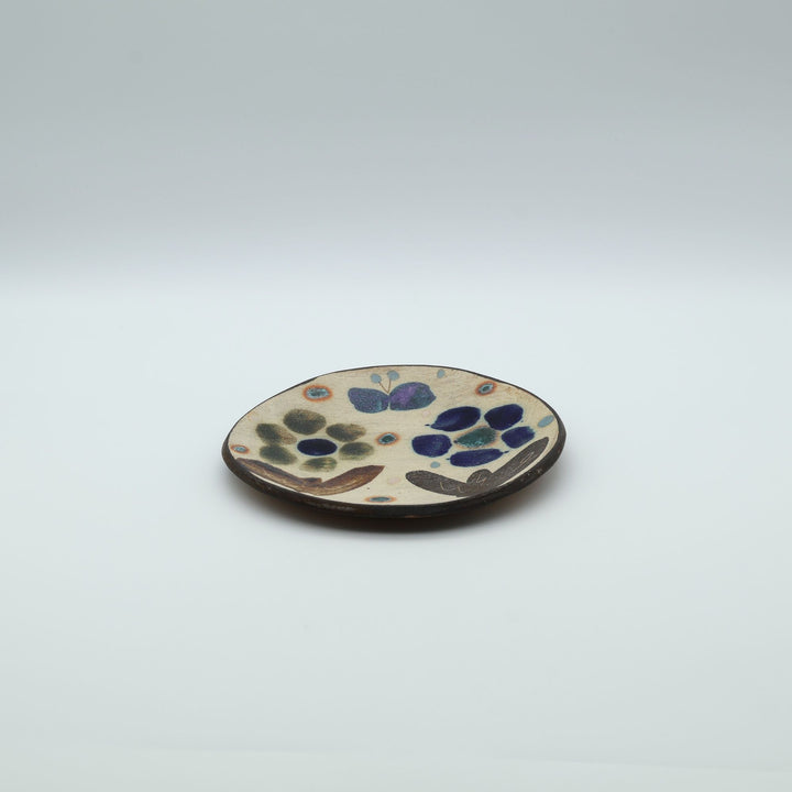 沖縄のやちむん工房「土の種」のサラダ皿。花に舞う蝶や鳥が大胆に絵付けされた手仕事の平皿。