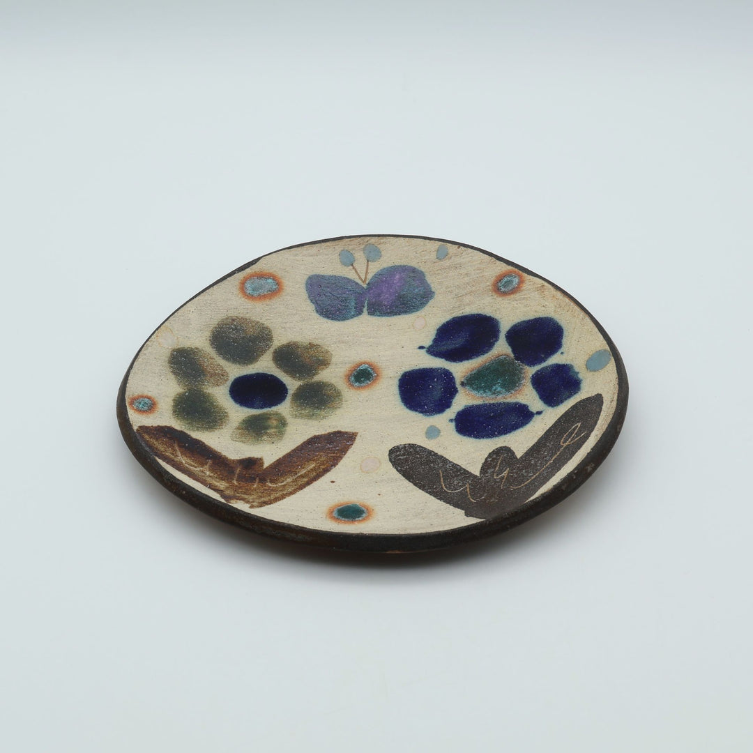 沖縄のやちむん工房「土の種」のサラダ皿。花に舞う蝶や鳥が大胆に絵付けされた手仕事の平皿。