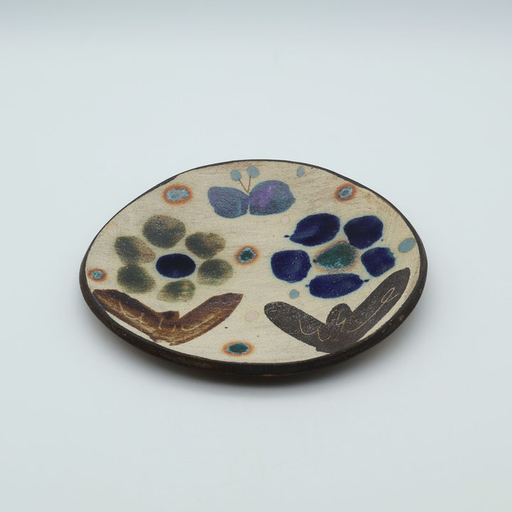 沖縄のやちむん工房「土の種」のサラダ皿。花に舞う蝶や鳥が大胆に絵付けされた手仕事の平皿。