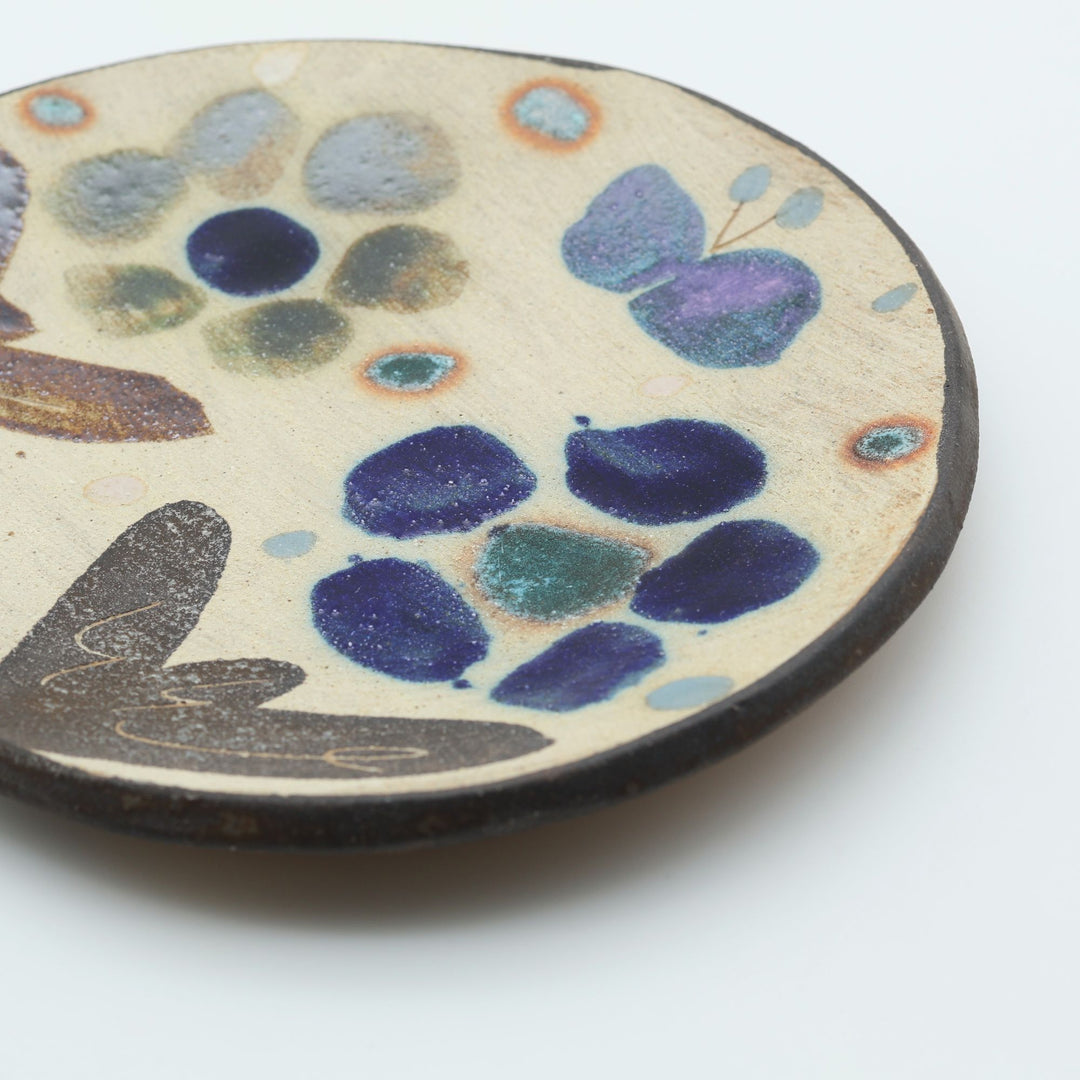沖縄のやちむん工房「土の種」のサラダ皿。花に舞う蝶や鳥が大胆に絵付けされた手仕事の平皿。