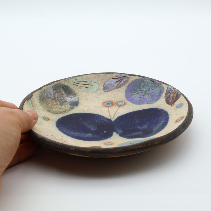 沖縄のやちむん工房「土の種」のサラダ皿。鮮やかなコバルトブルーの蝶が大胆に絵付けされた手仕事の平皿。