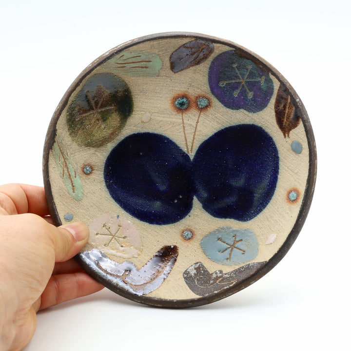 沖縄のやちむん工房「土の種」のサラダ皿。鮮やかなコバルトブルーの蝶が大胆に絵付けされた手仕事の平皿。