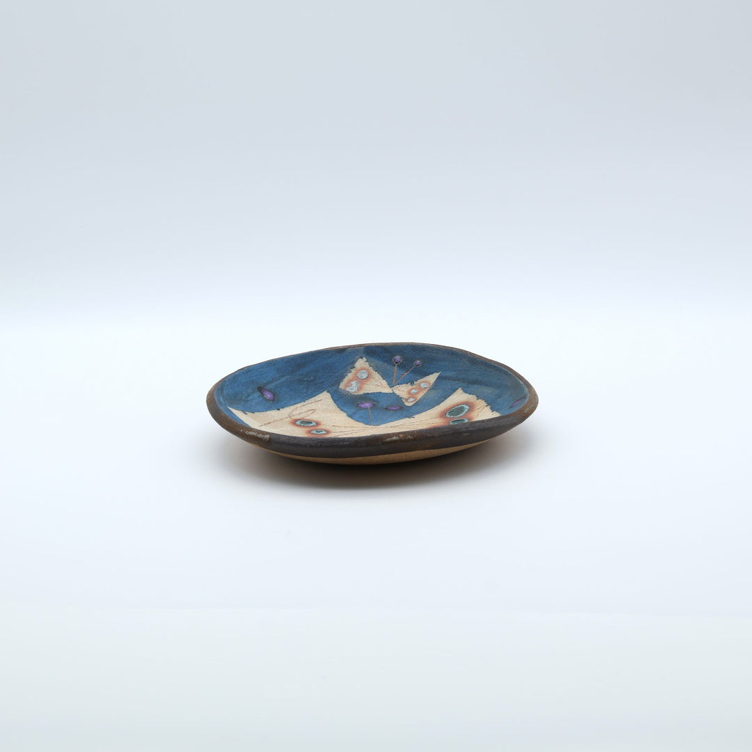 沖縄のやちむん工房「土の種」のサラダ皿。鮮やかなコバルトブルーの地色に、蝶が絵付けされた手仕事の平皿。