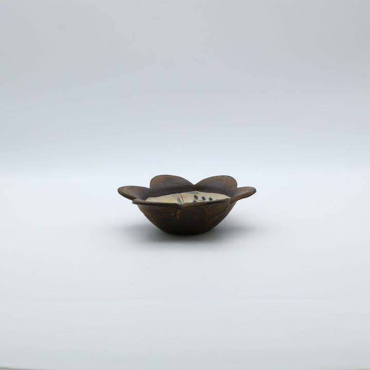 やちむん工房「土の種」の愛らしいふっくらとしたお花型の小鉢。内側に優しく素朴なタッチで植物や小さな花々が絵付けされた、沖縄の手仕事による1点もののうつわ。