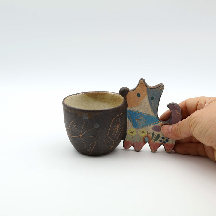 いぬをモチーフにした持ち手が愛らしい、沖縄県うるま市「土の種」の陶器フリーカップ。手描きの絵付けが施されたやちむんの器。デスクの上の小物入れとしても。
