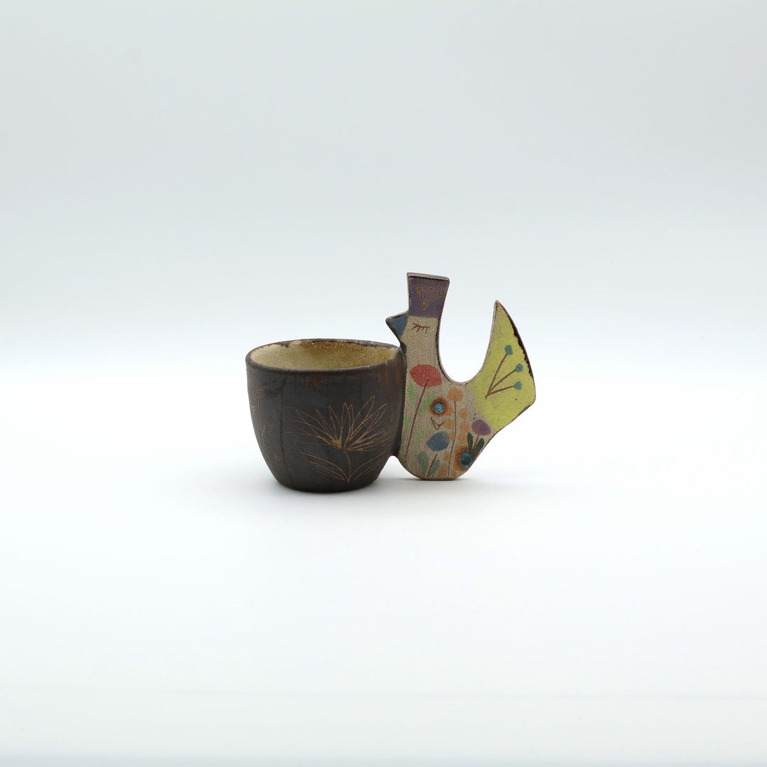 トリをモチーフにした持ち手が特徴的な、陶器のフリーカップ。素朴な土の質感と絵付けが施された沖縄のやちむん。