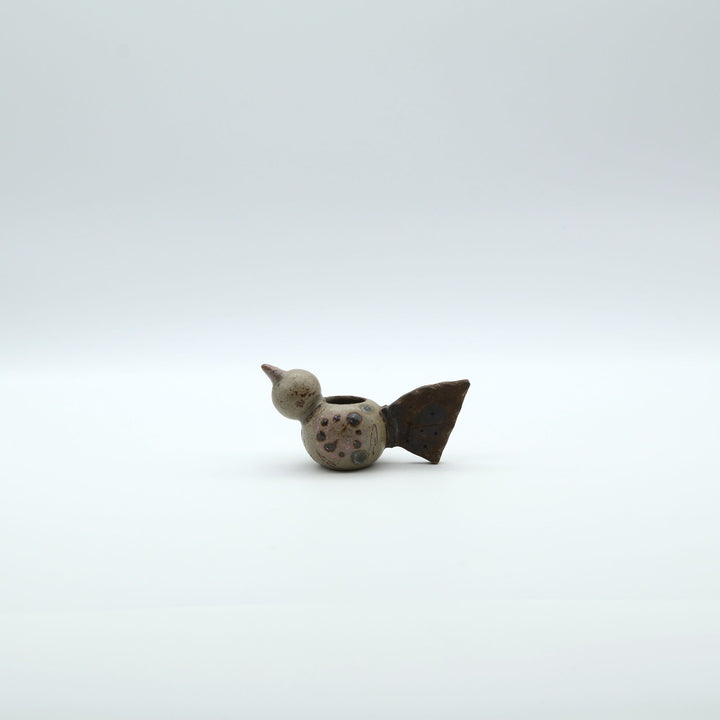 沖縄のやちむん作家「土の種」による、コロンとした鳥の形をした愛らしいミニ花器（一輪挿し・楊枝入れ）。背中に穴が開いており、素朴な土の風合いとオブジェとしての可愛らしさを併せ持つ陶器。