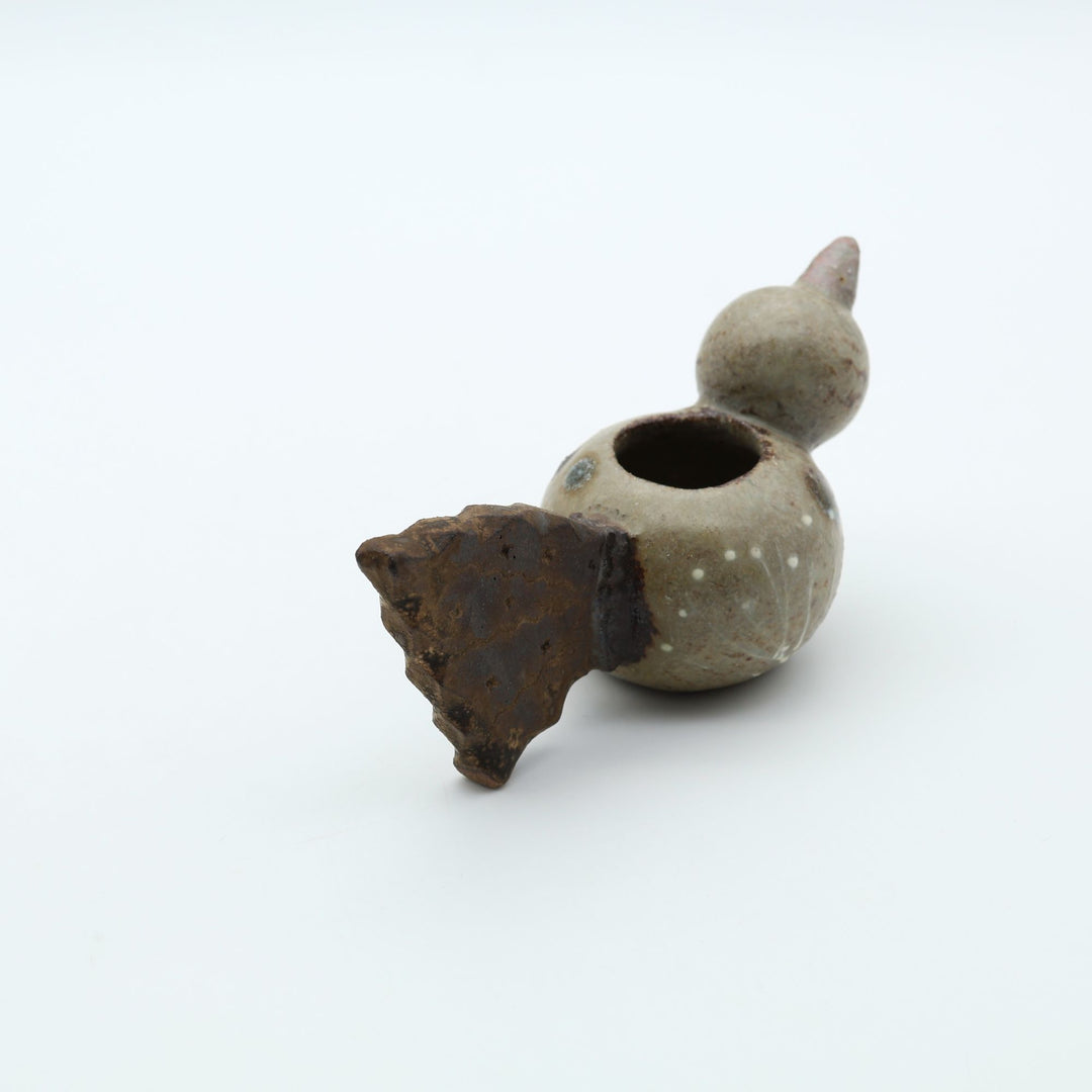 沖縄のやちむん作家「土の種」による、コロンとした鳥の形をした愛らしいミニ花器（一輪挿し・楊枝入れ）。背中に穴が開いており、素朴な土の風合いとオブジェとしての可愛らしさを併せ持つ陶器。