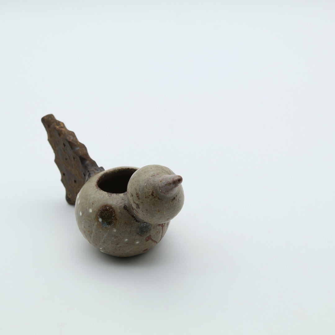 沖縄のやちむん作家「土の種」による、コロンとした鳥の形をした愛らしいミニ花器（一輪挿し・楊枝入れ）。背中に穴が開いており、素朴な土の風合いとオブジェとしての可愛らしさを併せ持つ陶器。