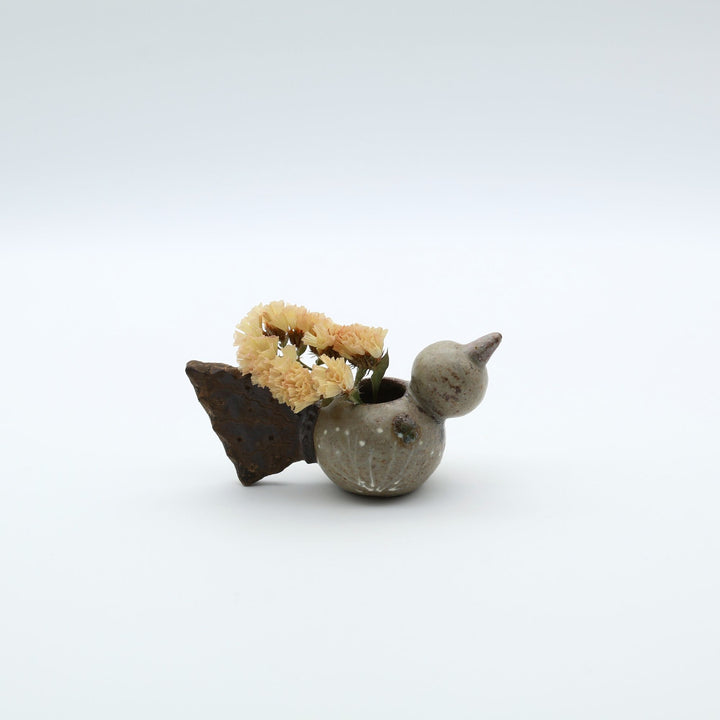 沖縄のやちむん作家「土の種」による、コロンとした鳥の形をした愛らしいミニ花器（一輪挿し・楊枝入れ）。背中に穴が開いており、素朴な土の風合いとオブジェとしての可愛らしさを併せ持つ陶器。