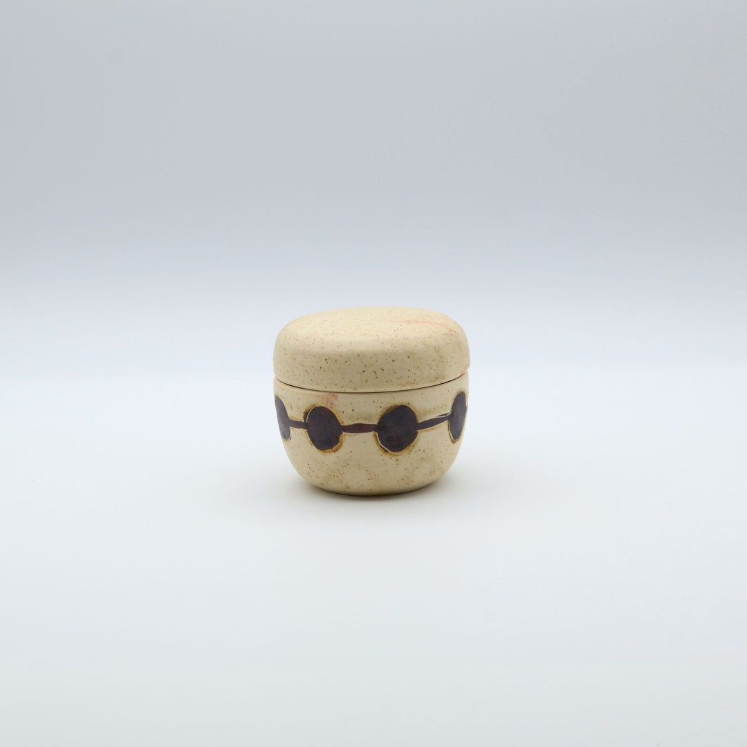 sora potters workによる、温かみのあるベージュの器肌に丸と線の模様が描かれた、蓋が添えられたやちむんの蓋物（キャニスター）
