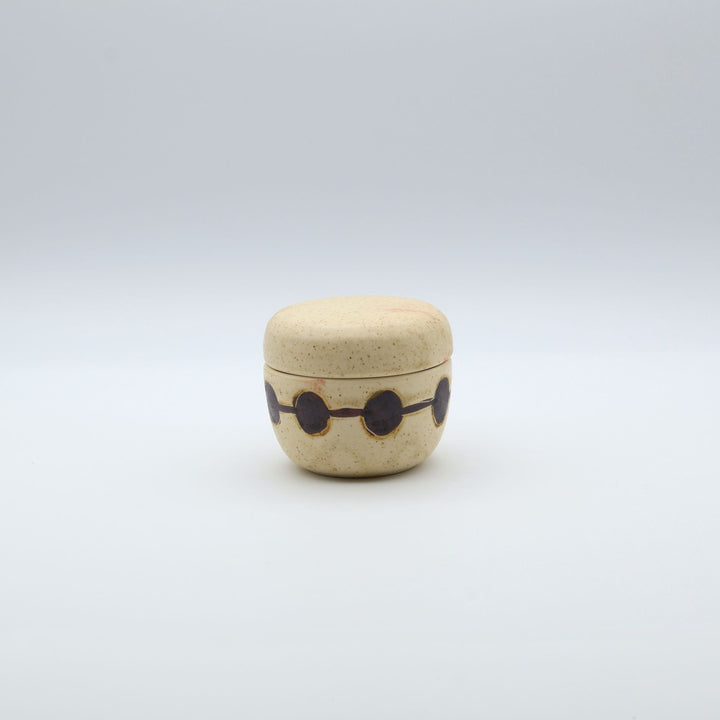 sora potters workによる、温かみのあるベージュの器肌に丸と線の模様が描かれた、蓋が添えられたやちむんの蓋物（キャニスター）