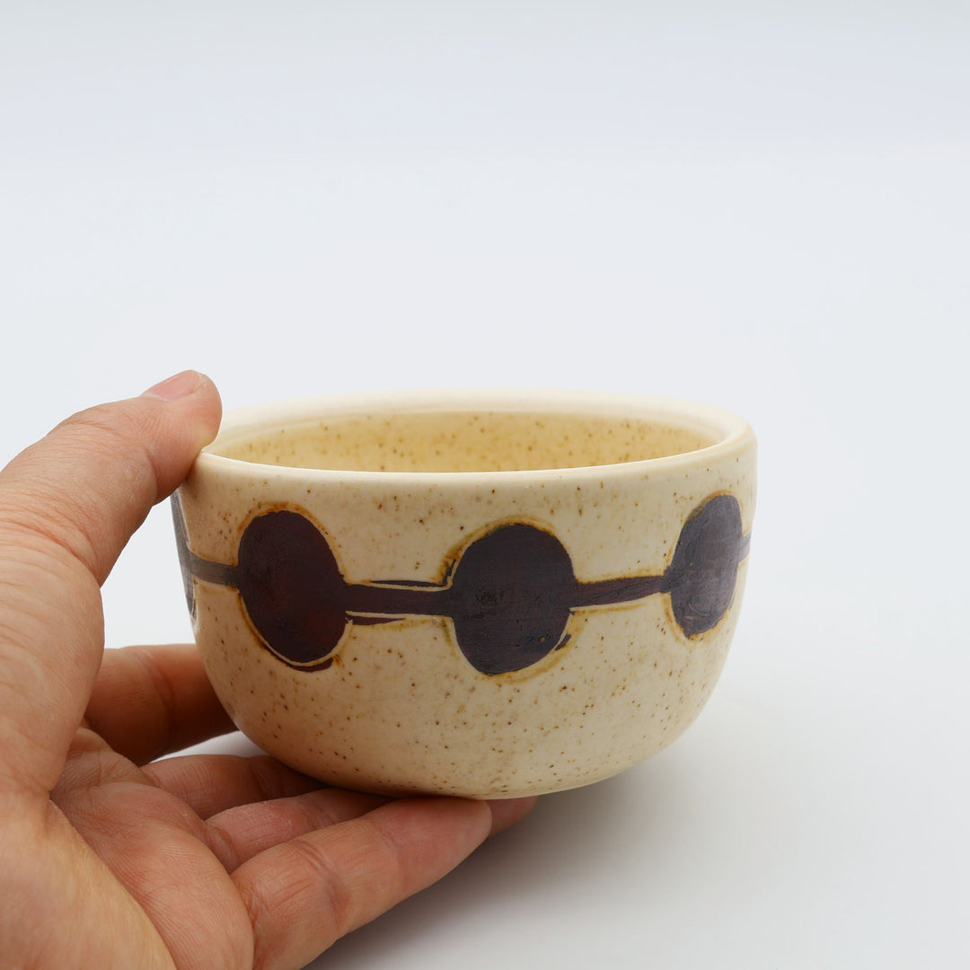 sora potters workによる、温かみのあるベージュの器肌に丸と線の模様が描かれた、蓋が添えられたやちむんの蓋物（キャニスター）