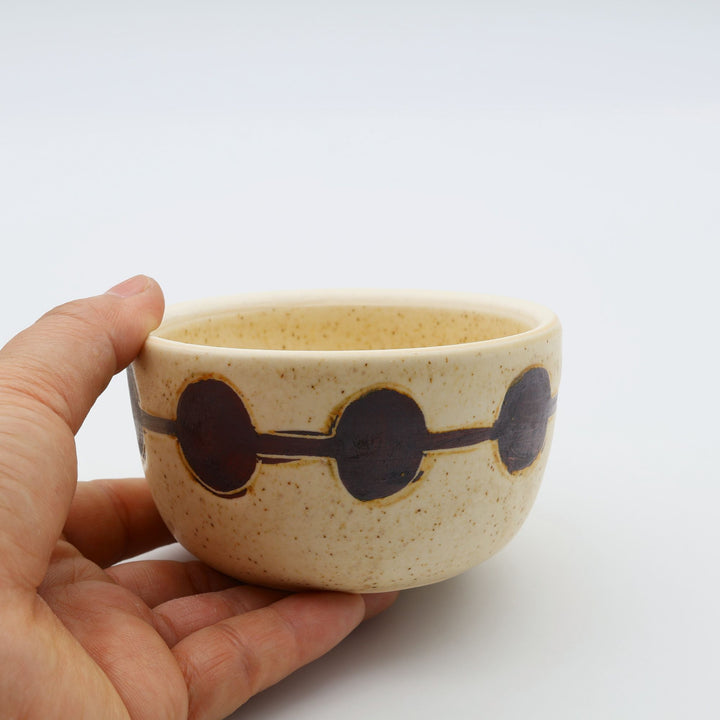 sora potters workによる、温かみのあるベージュの器肌に丸と線の模様が描かれた、蓋が添えられたやちむんの蓋物（キャニスター）