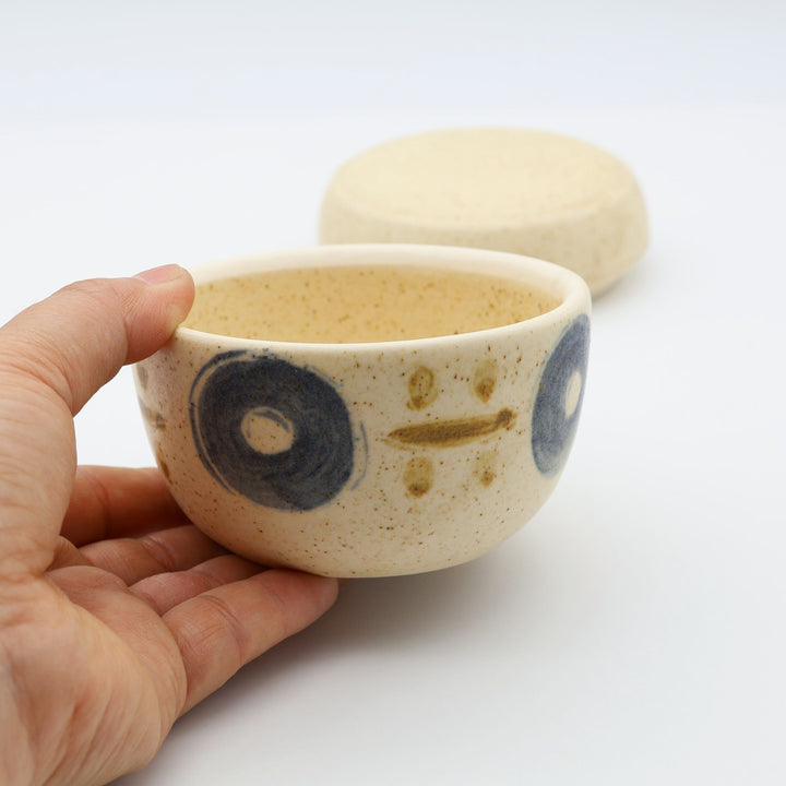 sora potters workによる、温かみのあるベージュの器肌に伝統的なやちむん柄をSPW風にアレンジしたモダンな模様が描かれた小さな蓋物。