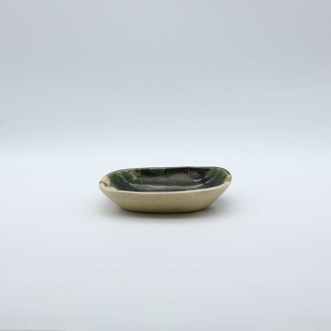 宋艸窯（そうそうがま）が異なる色の粘土を組み合わせて作った、練り込み技法に緑釉を半分に掛け分けた長方形の小皿。緑と白背景の中央に置かれた、モダンな幾何学模様と丸みのあるフォルムが美しい手仕事の豆皿です。