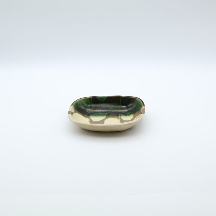 宋艸窯（そうそうがま）が異なる色の粘土を組み合わせて作った、練り込み技法に緑釉を半分に掛け分けた長方形の小皿。緑と白背景の中央に置かれた、モダンな幾何学模様と丸みのあるフォルムが美しい手仕事の豆皿です。