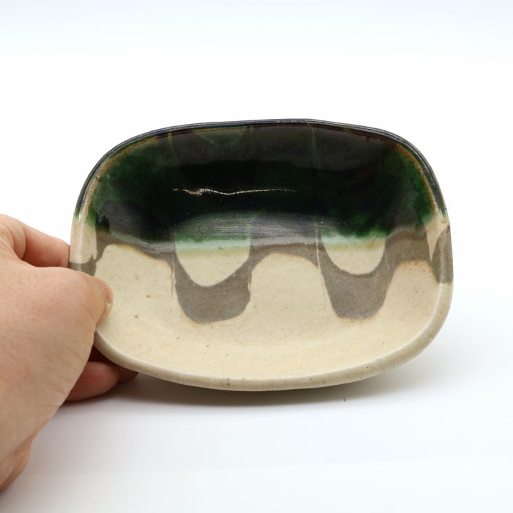 宋艸窯（そうそうがま）が異なる色の粘土を組み合わせて作った、練り込み技法に緑釉を半分に掛け分けた長方形の小皿。緑と白背景の中央に置かれた、モダンな幾何学模様と丸みのあるフォルムが美しい手仕事の豆皿です。