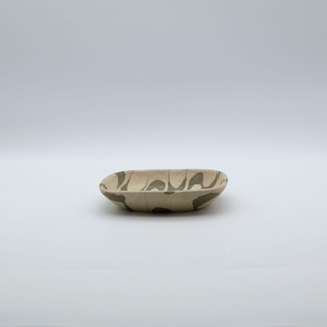 宋艸窯（そうそうがま）が異なる色の粘土を組み合わせて作った、練り込み技法の長方形の小皿。白背景の中央に置かれた、モダンな幾何学模様と丸みのあるフォルムが美しい手仕事の豆皿です。