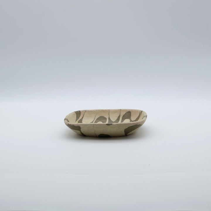 宋艸窯（そうそうがま）が異なる色の粘土を組み合わせて作った、練り込み技法の長方形の小皿。白背景の中央に置かれた、モダンな幾何学模様と丸みのあるフォルムが美しい手仕事の豆皿です。