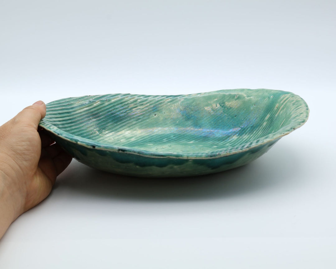 北海道洞爺湖の陶芸家・沼田佳奈子作、鮮やかなグリーンの釉薬と立体的な櫛目が施された手びねりの深皿。白を基調とした背景に、海中のような淡緑のグラデーションが美しい大皿が佇む1点ものの作品。canosa取扱商品。