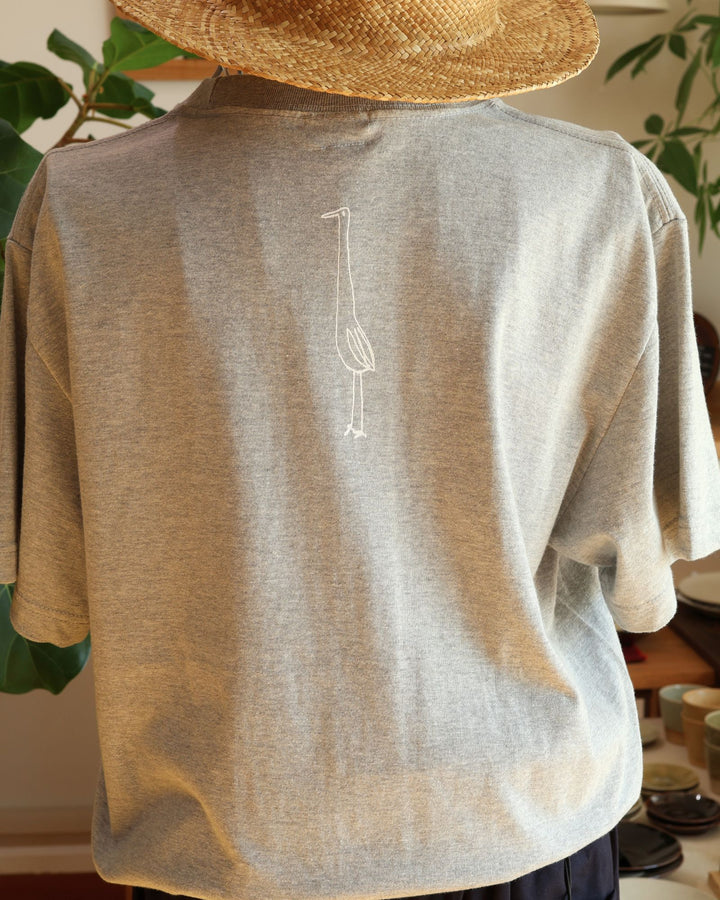 沖縄の工房、Doucatty（ドゥカティ）の手捺染Tシャツ「King of The World」の背面。背中の首元下に、白の細い線画で一本足で佇む水鳥（サギ）がワンポイントでプリントされている。