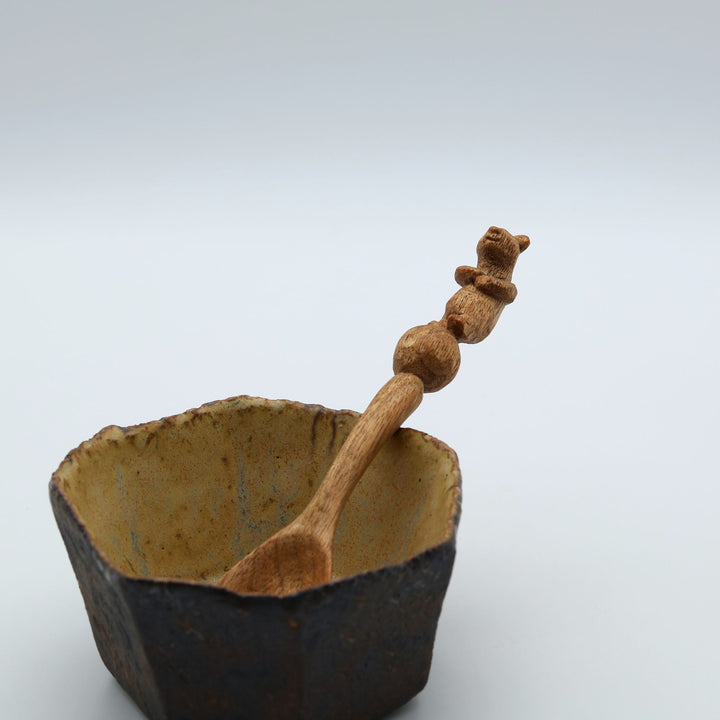 北海道の作家、木工YOUSUN（ヨウサン）が地元のクルミを丁寧に削り出して作った木製コーヒースプーン。柄の先端に上手な玉乗りをする可愛いクマが彫られた、手仕事の温かみを感じるカトラリーです。