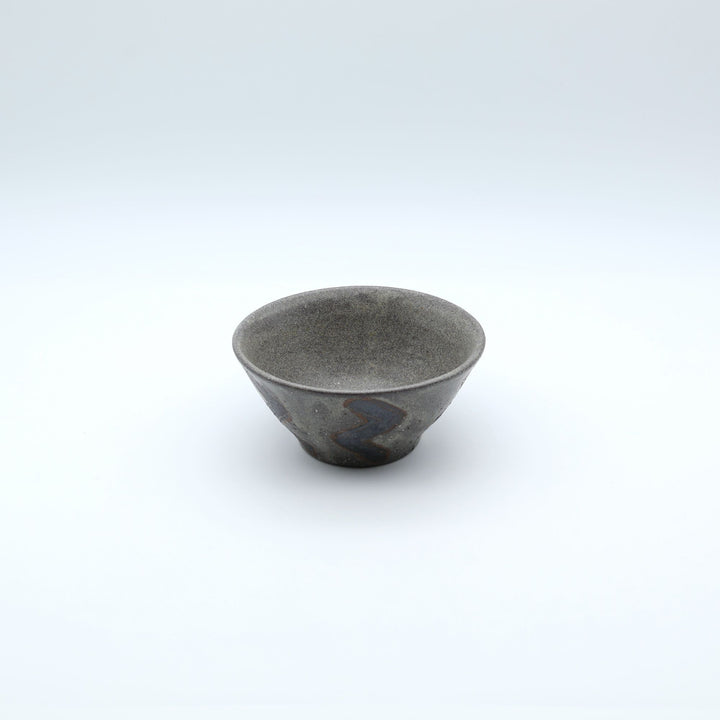 sora potters workによる、ザラりとした渋い鉄砂の器肌にジグザグの線紋が大胆に描かれた手作りのマカイ（お茶碗）。