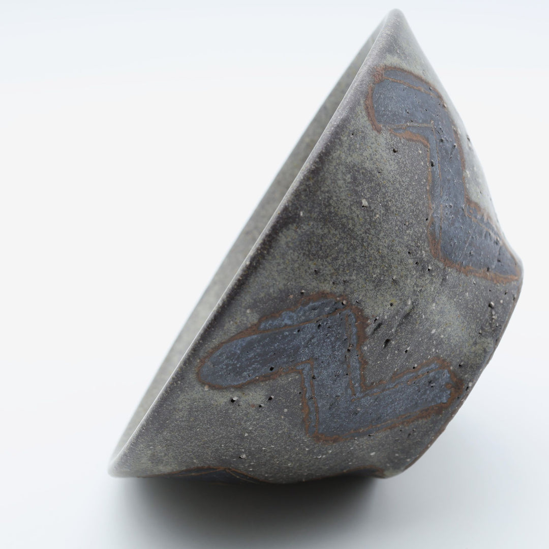 sora potters workによる、ザラりとした渋い鉄砂の器肌にジグザグの線紋が大胆に描かれた手作りのマカイ（お茶碗）。