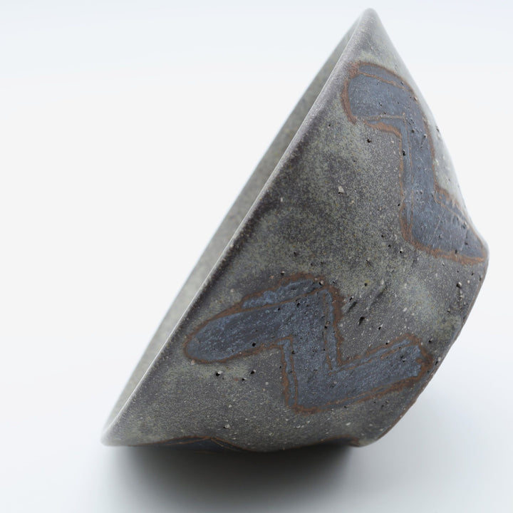sora potters workによる、ザラりとした渋い鉄砂の器肌にジグザグの線紋が大胆に描かれた手作りのマカイ（お茶碗）。