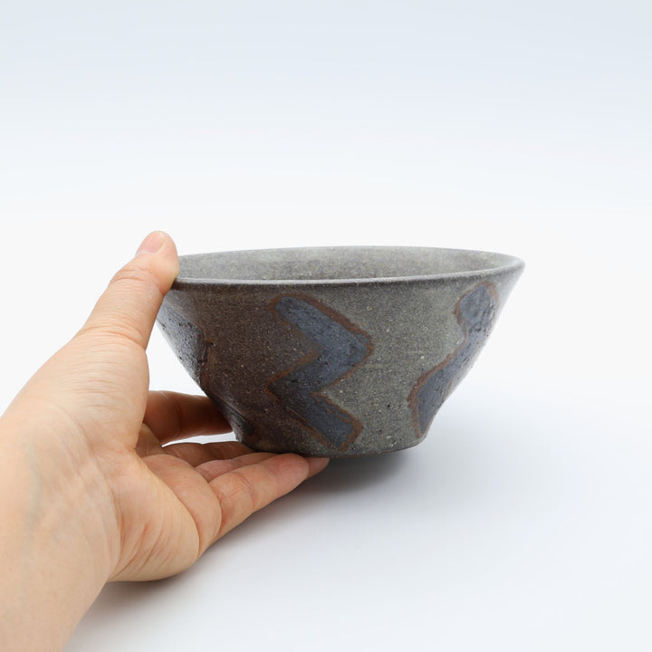 sora potters workによる、ザラりとした渋い鉄砂の器肌にジグザグの線紋が大胆に描かれた手作りのマカイ（お茶碗）。