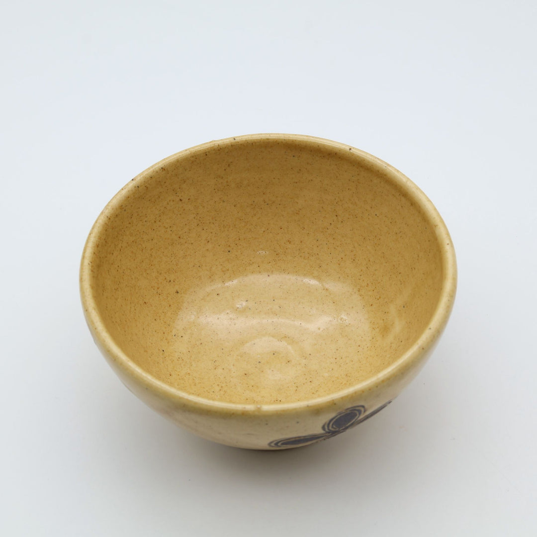 sora potters workによる、温かみのあるベージュの器肌十字花模様が描かれた手作りのお茶碗-マカイ