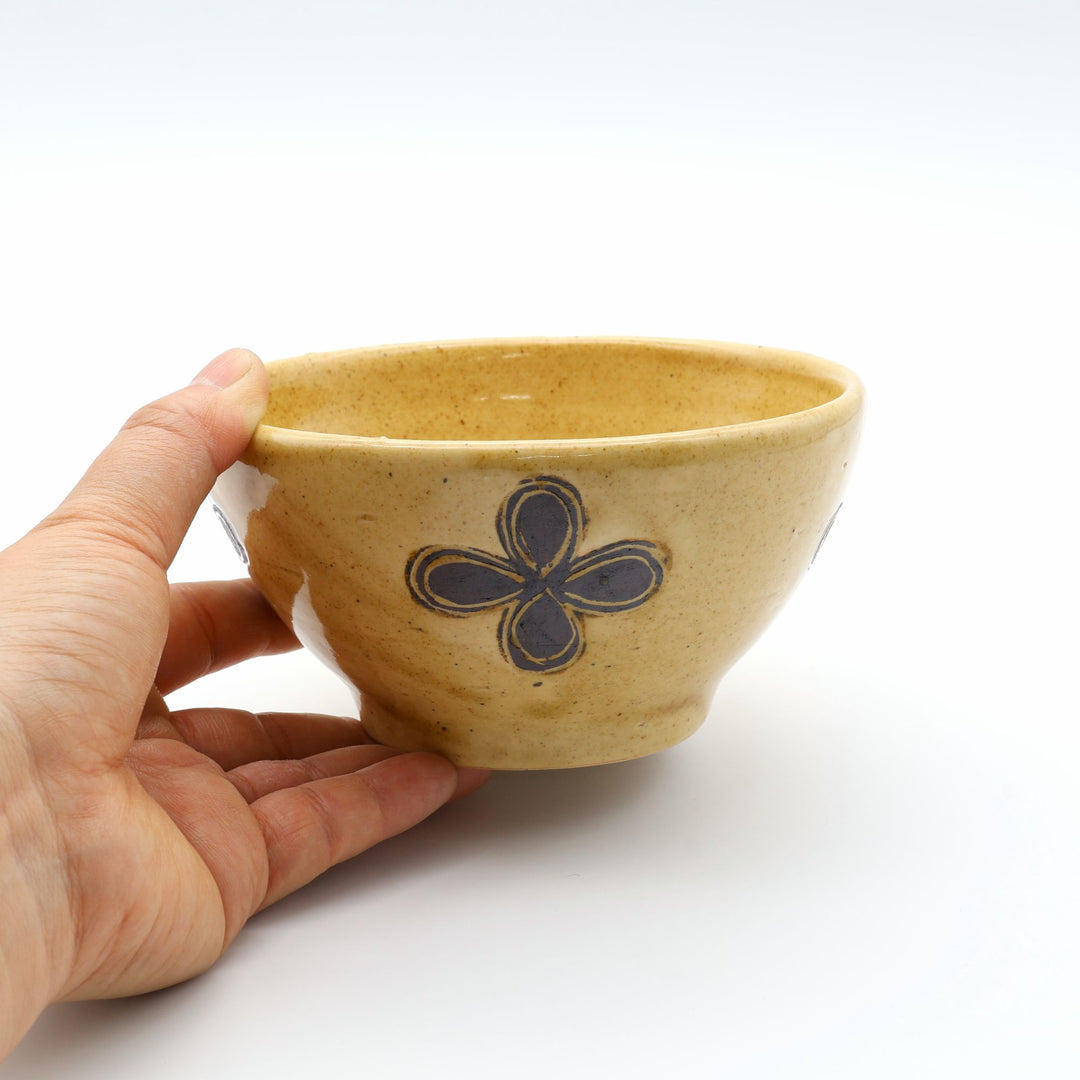 sora potters workによる、温かみのあるベージュの器肌十字花模様が描かれた手作りのお茶碗-マカイ