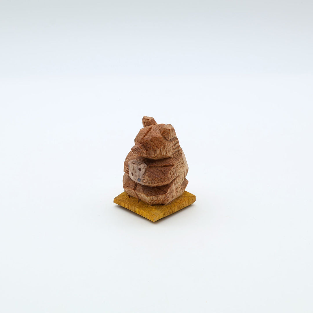 岐阜の木彫り熊作家「gizakuma」が彫る、大切そうに「やちむん」の湯呑みでお茶を飲んでいる「くま」。座布団の上でほっと一息ついてリラックスしている手彫りの木製オブジェ。