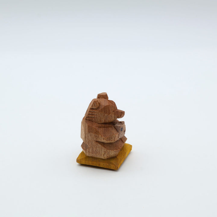 岐阜の木彫り熊作家「gizakuma」が彫る、大切そうに「やちむん」の湯呑みでお茶を飲んでいる「くま」。座布団の上でほっと一息ついてリラックスしている手彫りの木製オブジェ。