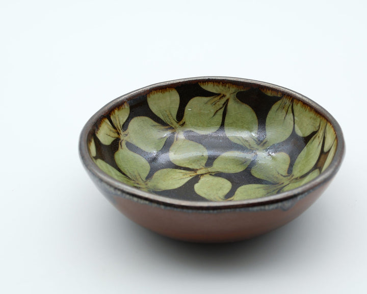 宮崎県生楽陶苑のスリップウェア。外側は素朴な茶系の陶器肌、内側に緑の花柄紋様が見える美しい小鉢。 